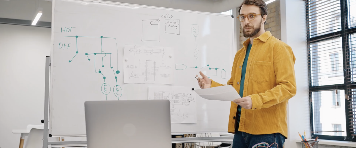 Man standing in front of whiteboard holding paper