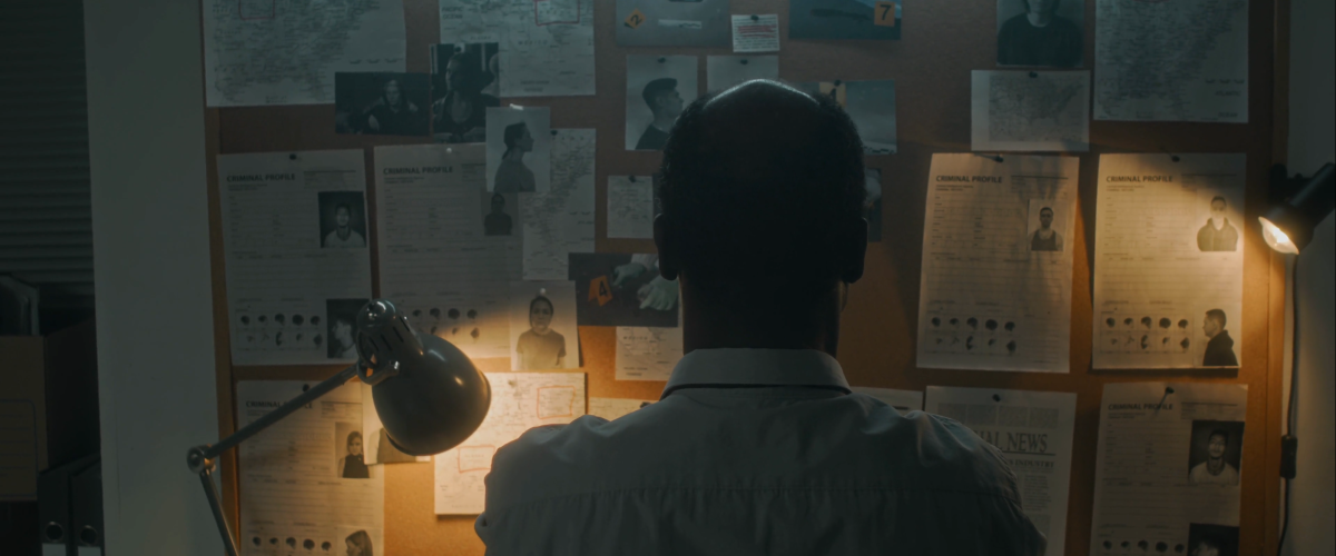 Detective looking at a cork board with evidence on it